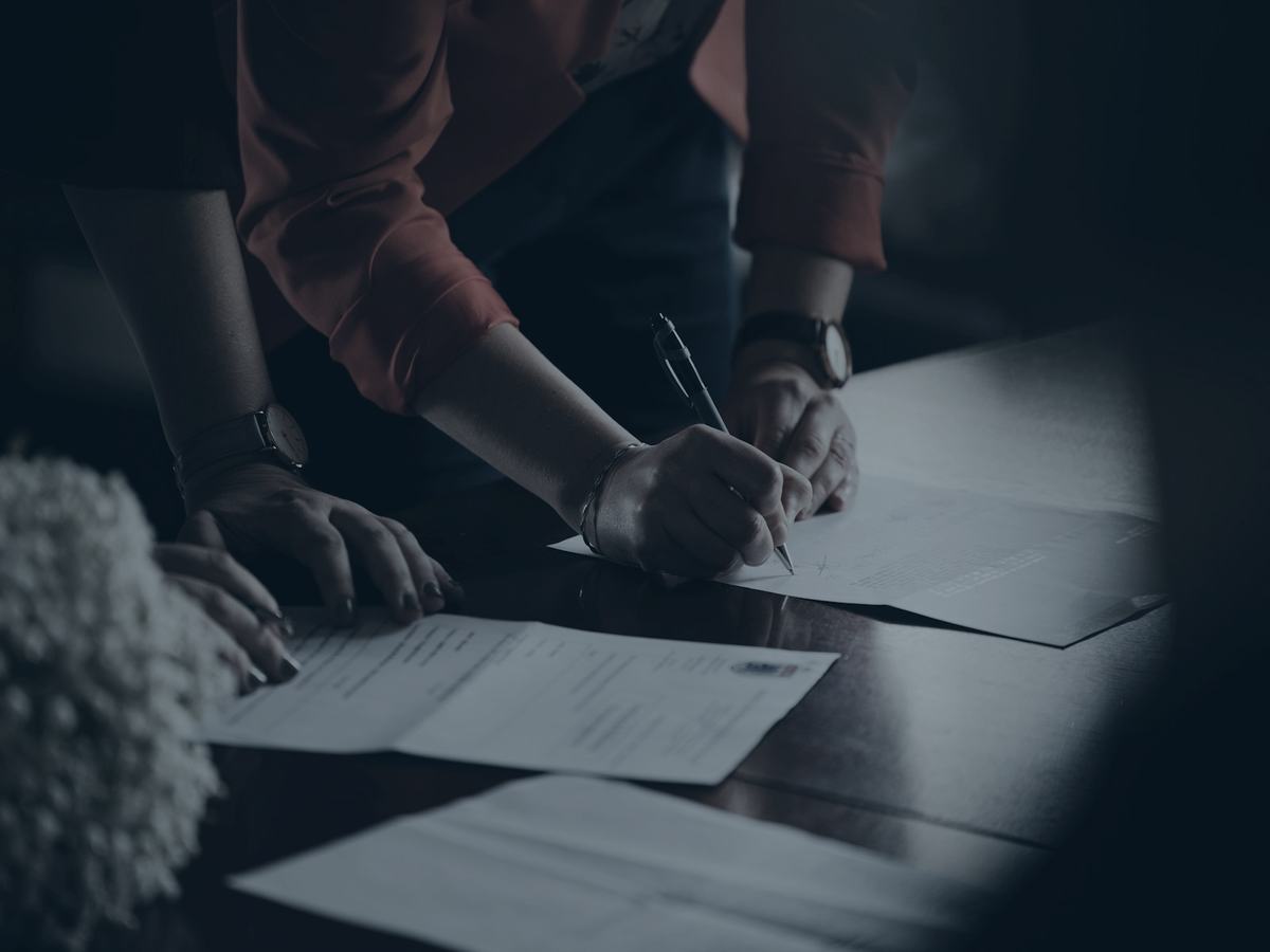 Duas pessoas conferindo e assinando um contrato sobre uma mesa